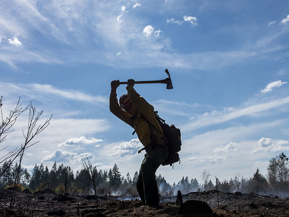 Ryan Whitmore, a member of the PatRick Crew, a private group based out of Redmond, Ore., digs up a hotspot at the Gish Road fire near Onalaska in this file photo.
