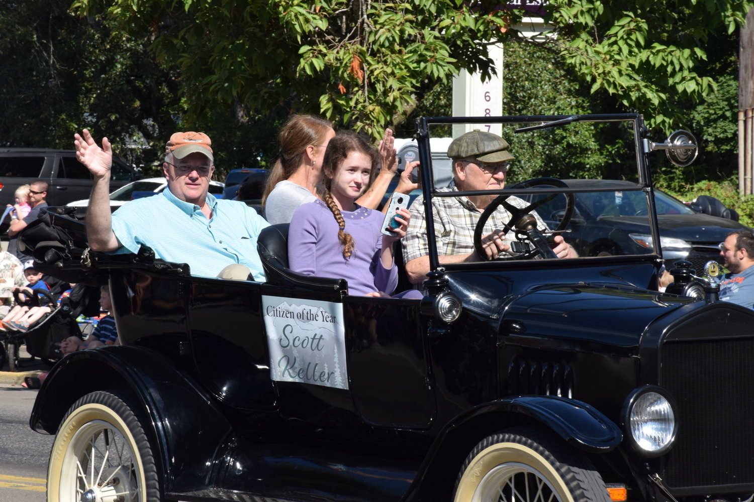 Battle Ground Citizen of the Year Scott Keller, left, rides in a vintage car as one of the first entries in the Battle Ground Harvest Days parade on July 17, 2021.