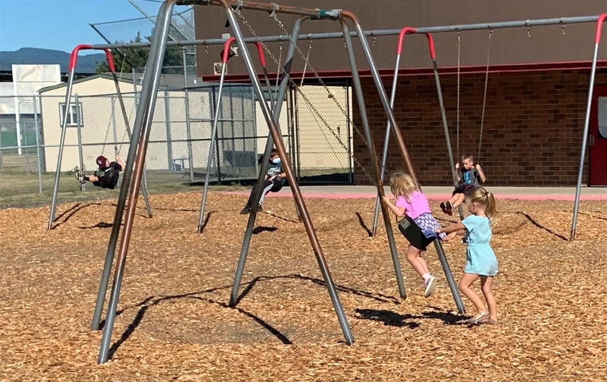 Children from Woodland Public Schools play on the swings.