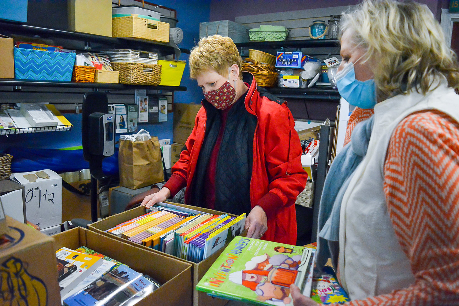Liz Cerveny, the executive director of North County Community Food Bank, and volunteer Ann Karr look over children’s books, which are included in some of the Christmas baskets the food bank will hand out.