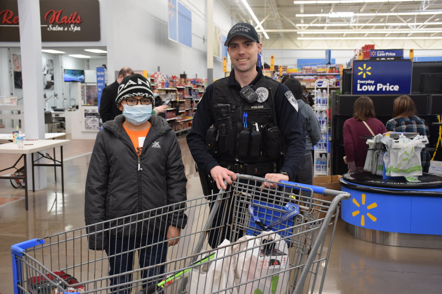 Osmar Gomez, left, stands by Woodland Police Department officer David Kerney after a successful haul from the Shop With a Cop event at the Woodland Walmart on Dec. 11.