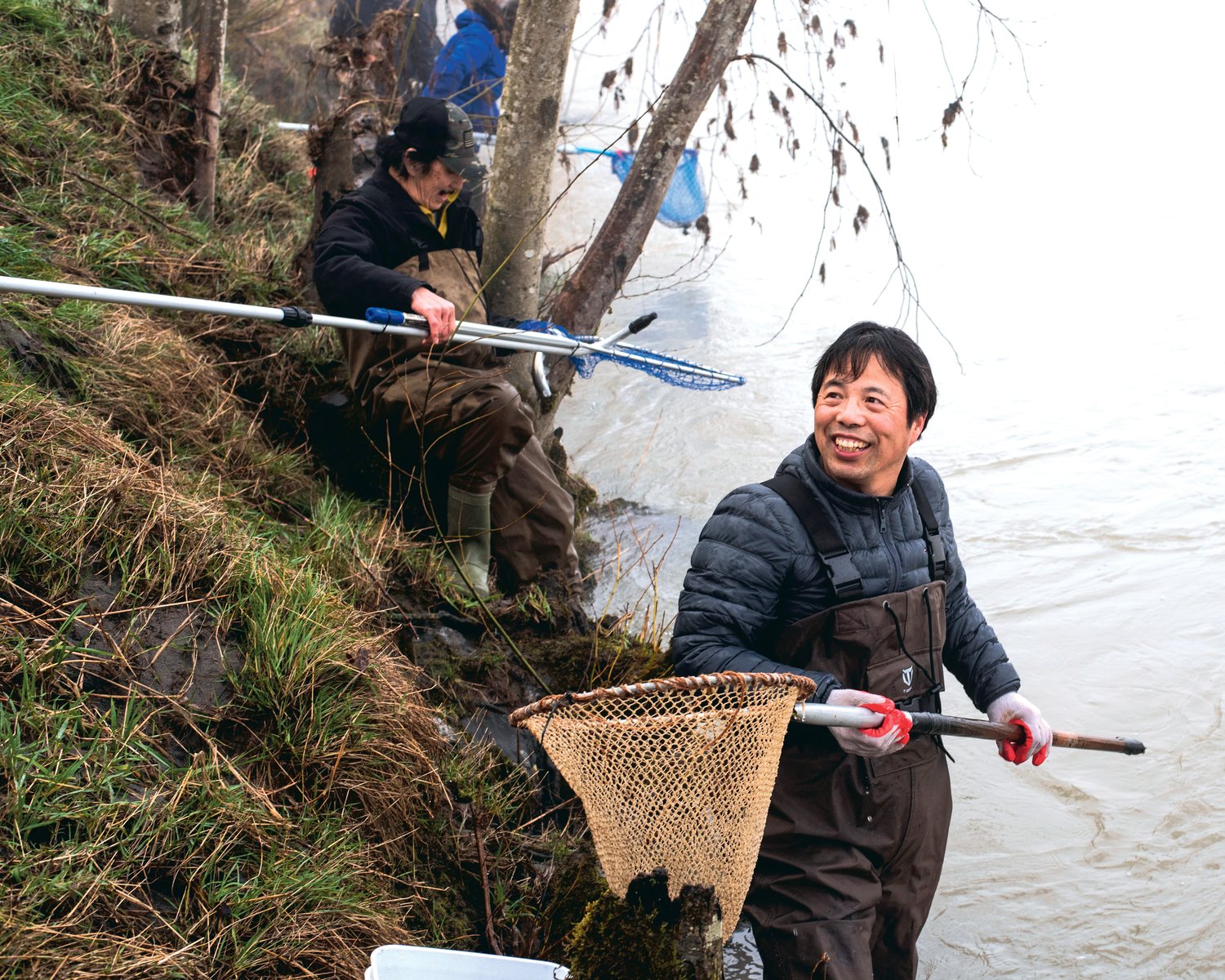 Xianping Tong smiles while dipping his net into the Cowlitz River Saturday morning in Castle Rock.