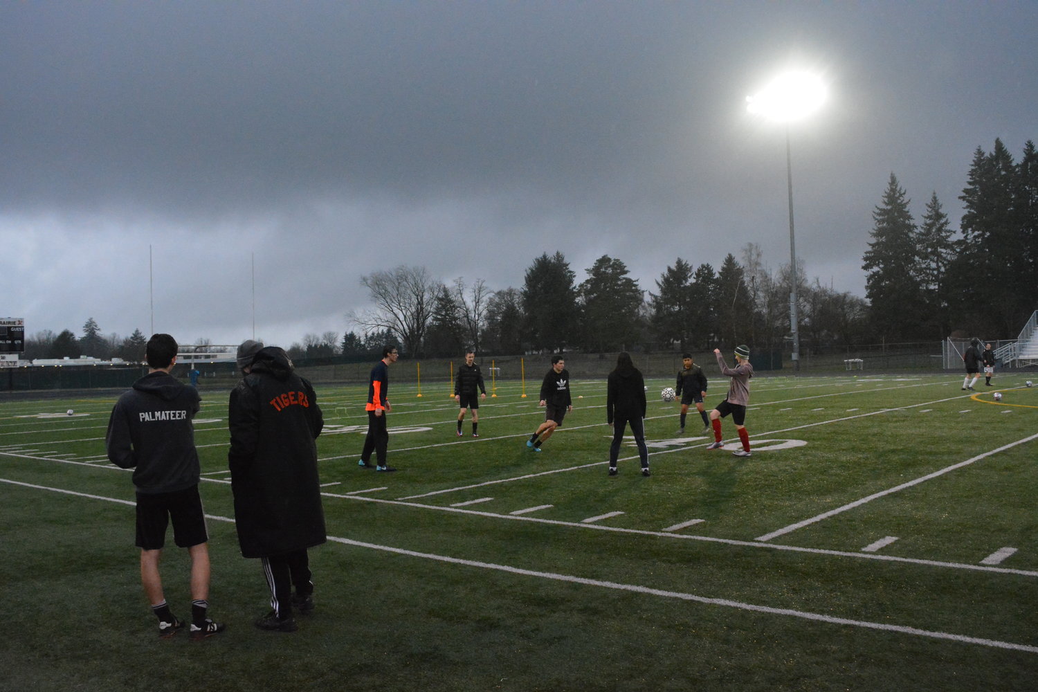 Boys kick the ball during tryouts as the soccer coaches look on March 2 at Battle Ground High School