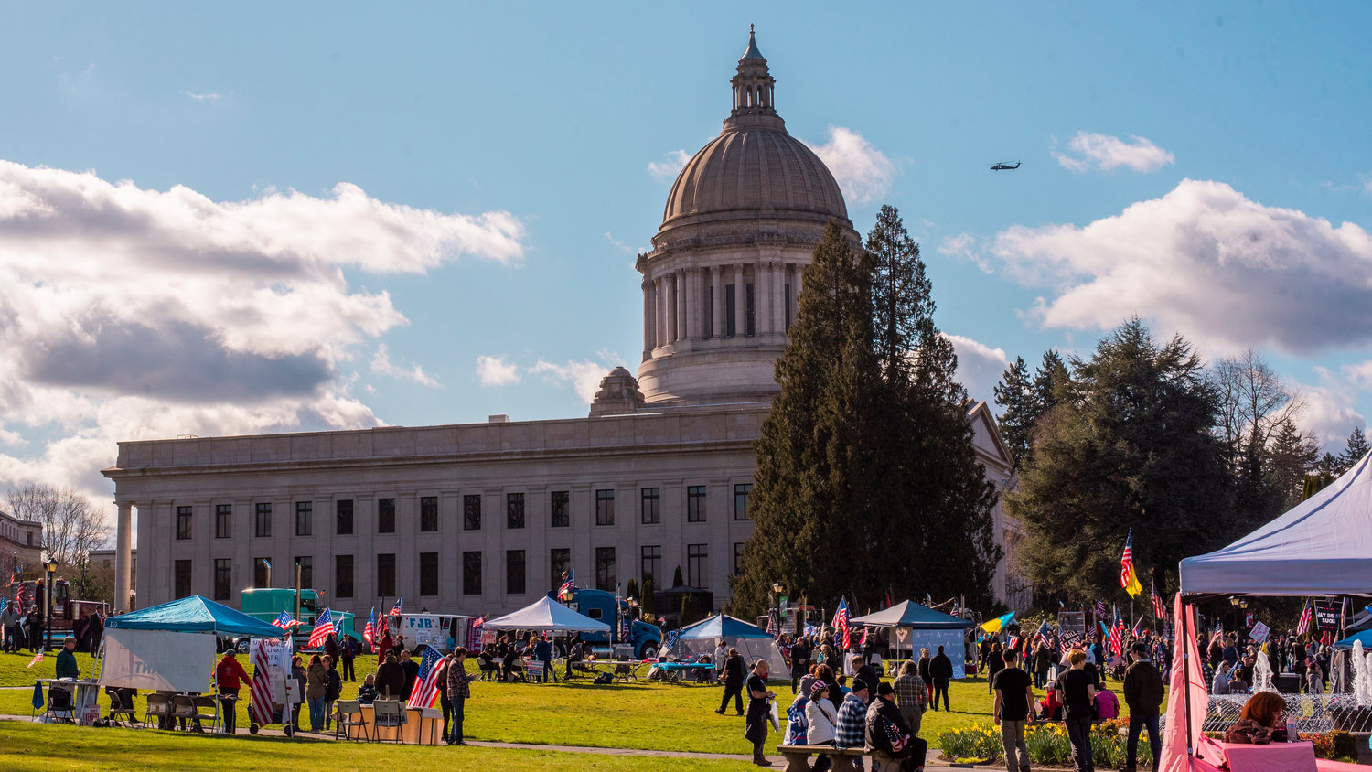 A helicopter flies around the Washington State Capitol Building in Olympia as demonstrators gather for the GRIT Freedom Festival Saturday afternoon.