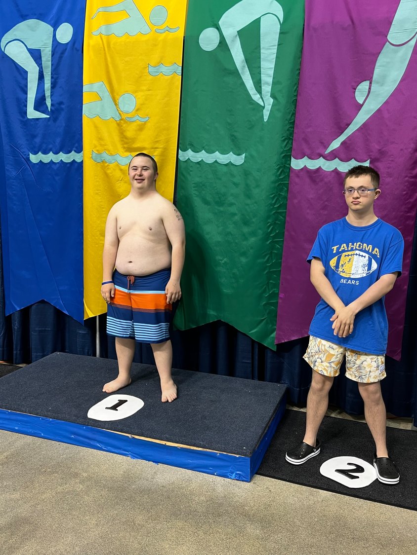 Hezekiah Hewes stands in the first place spot beside his teammate at the state unified Special Olympics swimming competition on June 19.