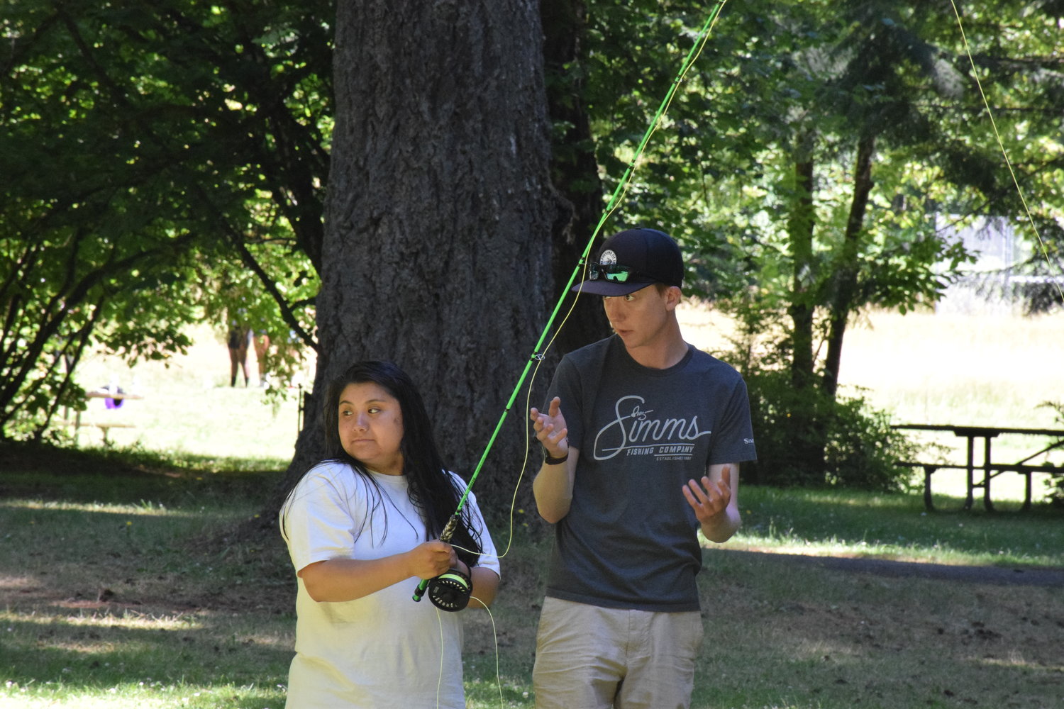Jackson Golik instructs Ruby Urbina on proper fly fishing casting techniques at Battle Ground Lake State Park on July 20.