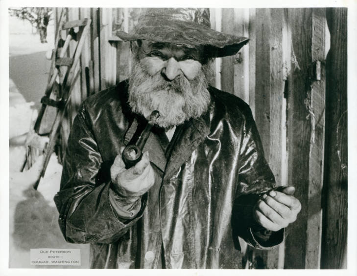 Ole Peterson stands on his property in the Lewis River area smoking a wooden pipe.