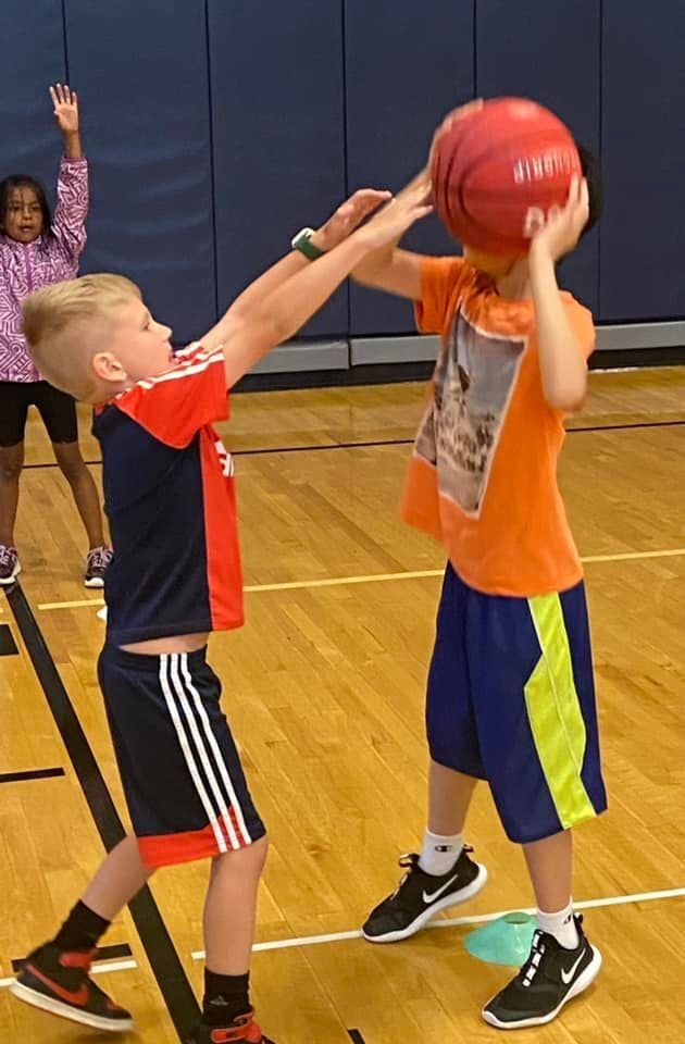A boy blocks another boy from scoring a basket at a QuickStart Sports basketball game.