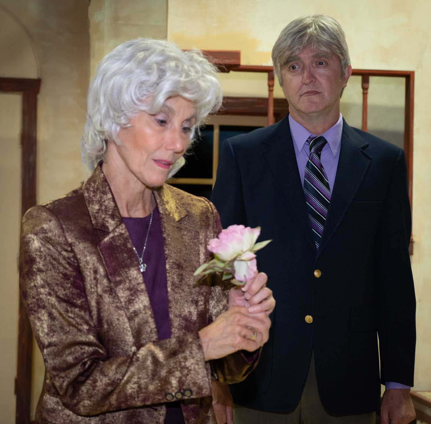 Alice Simms (Reba Hoffman, left) stares at a flower while Clark Simms (David Roberts, right) looks on from behind.