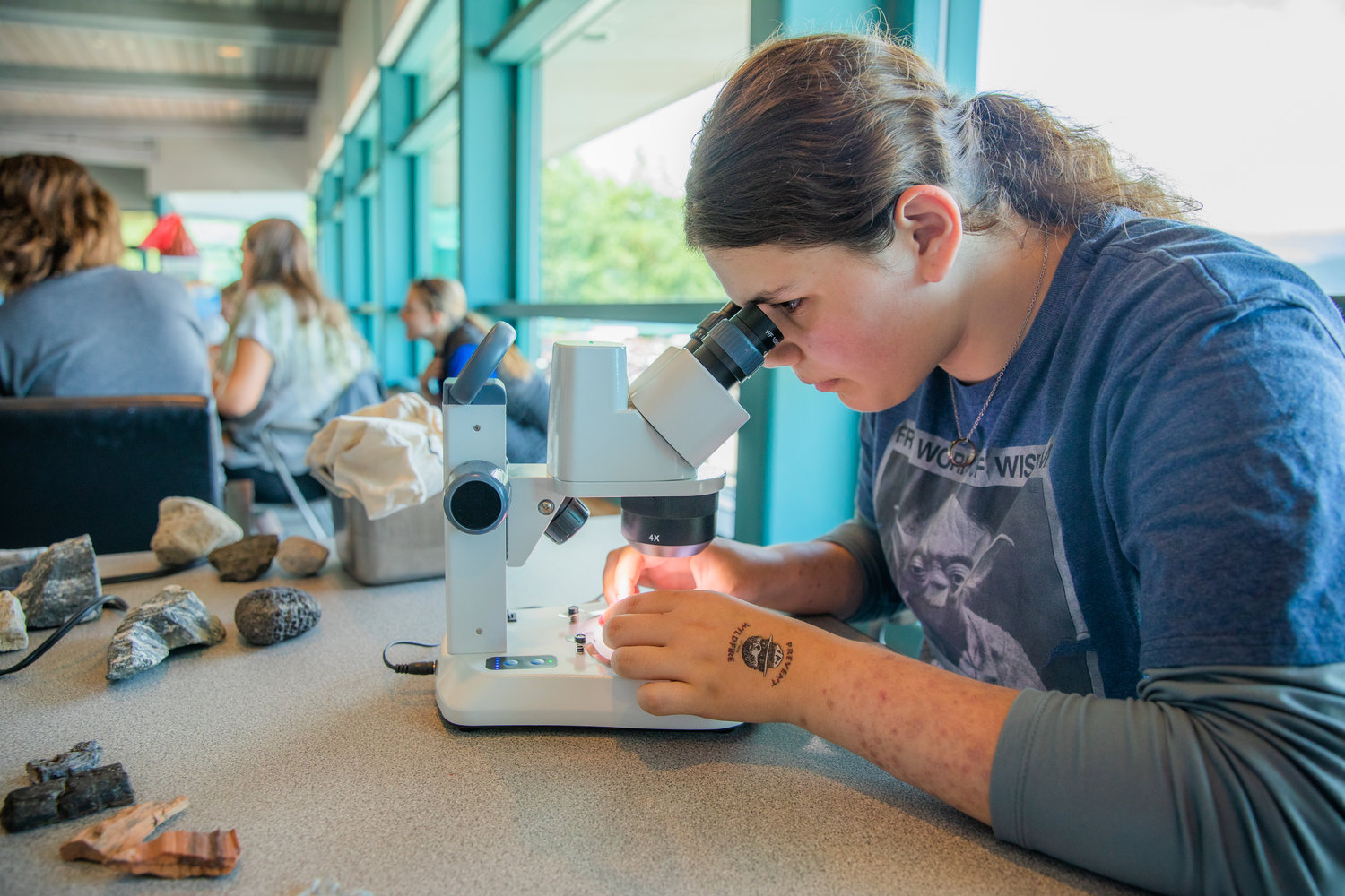 Paige Molyneux, 14, of Battle Ground, looks at rocks through a microscope during a GeoGirls project at the Mount St. Helens Science and Learning Center at Coldwater.