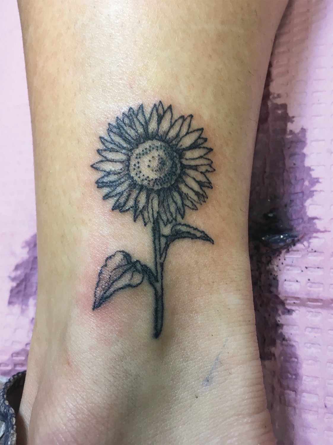 A sunflower tattoo inked by Chelsea Stowers.