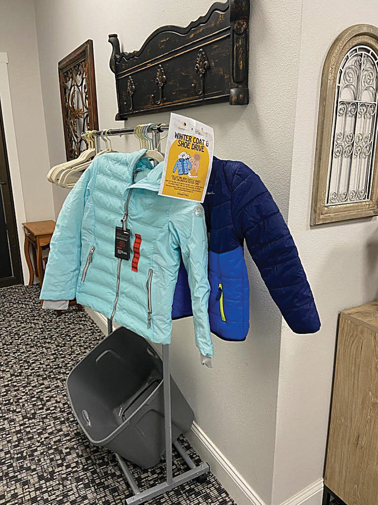 Coats collected for the coat and shoe drive hosted by Fosterful and Legions Realty hang on a rack.