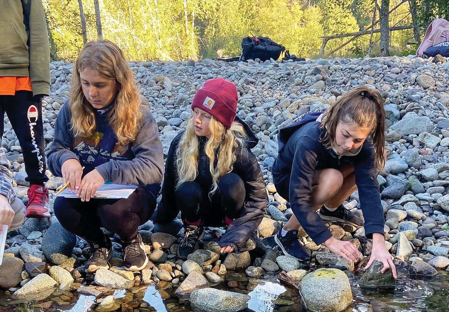 Ruby Stenbak, Jane Murri and Sophie Lanham collect water samples as part of a science lesson at the Cispus Outdoor School.