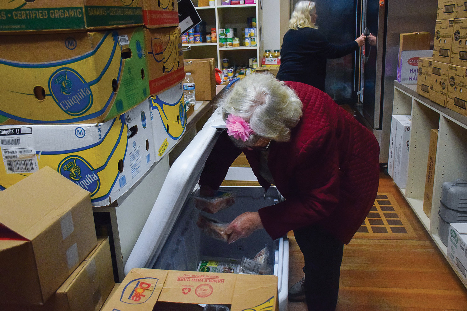 Gloria Chipman, a longtime volunteer with Neighbors Helping Neighbors, grabs food as she prepares a box for a client at the food bank on Nov. 22.