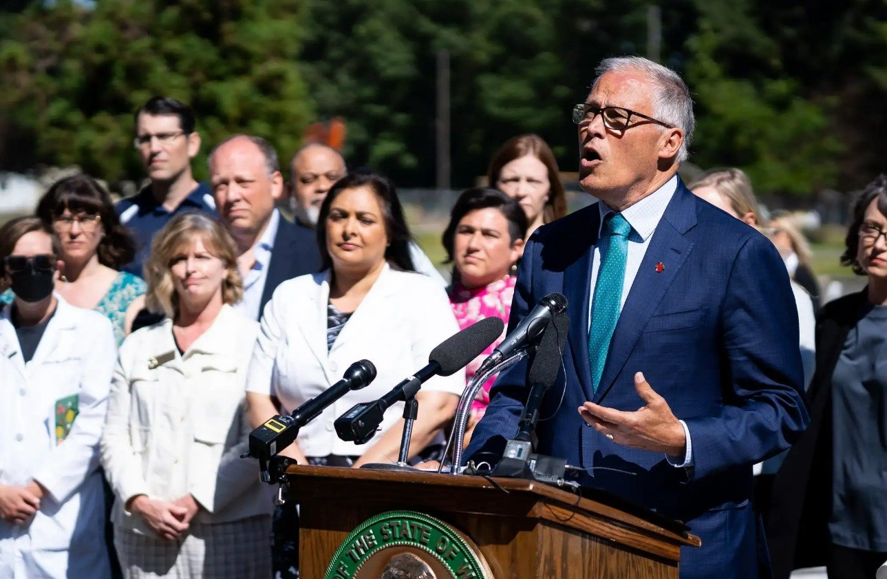 Gov. Jay Inslee is surrounded by legislators and reproductive health experts and advocates during a press conference responding to the Supreme Court’s decision in Dobbs v. Jackson Women’s Health Organization in June.