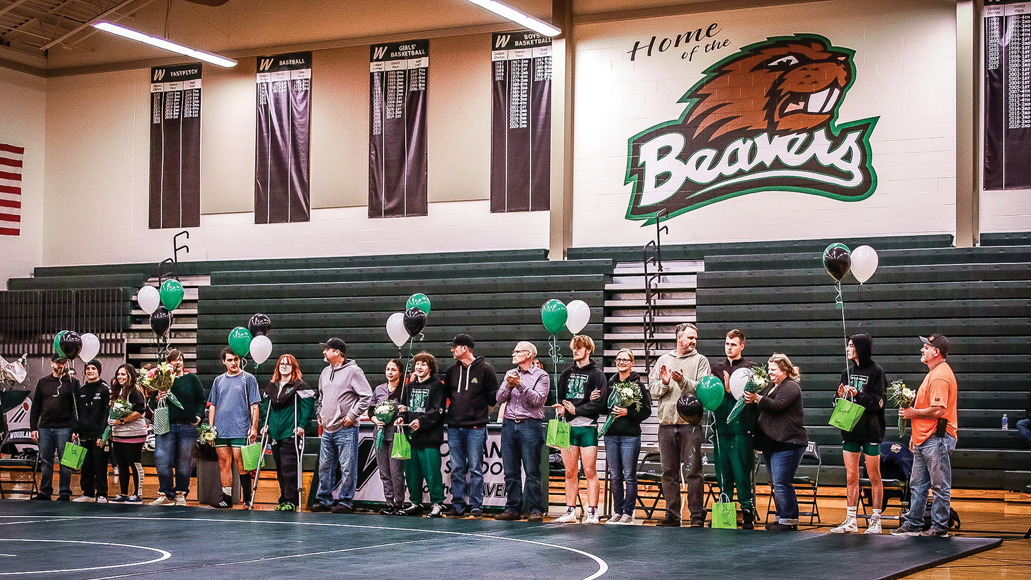 Seniors of the Woodland High School wrestling team stand with family members during senior night at home meet on Wednesday, Jan. 11.