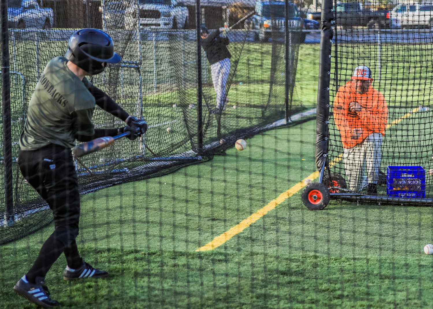 Varsity Head Coach Billy Hayes, right, pitches soft toss to the whole C-Team squad in the batting cages at the Battle Ground High School baseball fields on Wednesday, March 8.