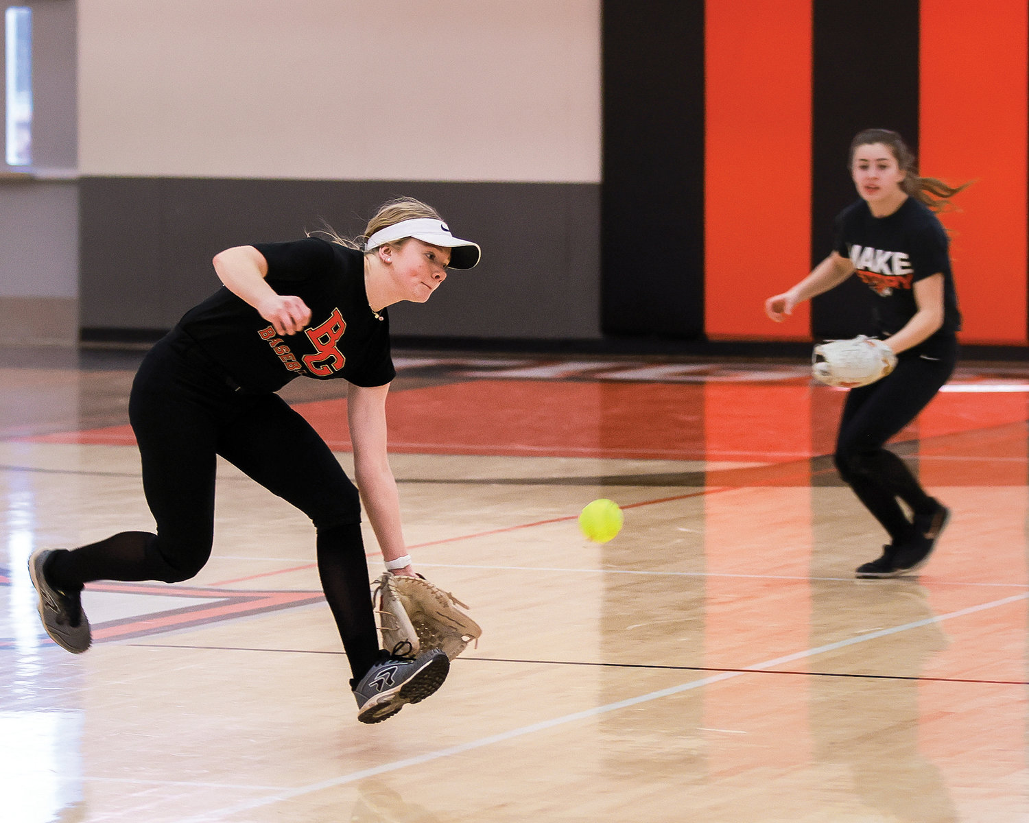 Hailey Ferguson fields a ball, left, while Lorelei Brown moves to backup a possible pass ball, right, during indoor defense drills at Battle Ground High School due to field conditions on Tuesday, March 7.