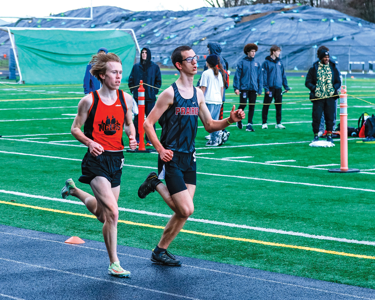 Battle Ground's Caden Ashworth runs alongside Prairie's Spencer Hoyt during the 3200-meter race at the Tiger Invite at Battle Ground High School on Saturday, March 25.