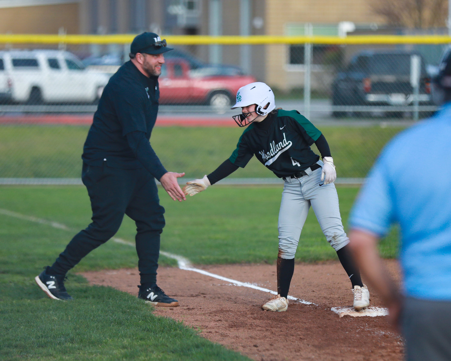 Head coach Tom Christensen high fives Madison Walker after she hit a seventh inning triple during Woodland's loss to Kelso on Wednesday, March 29.