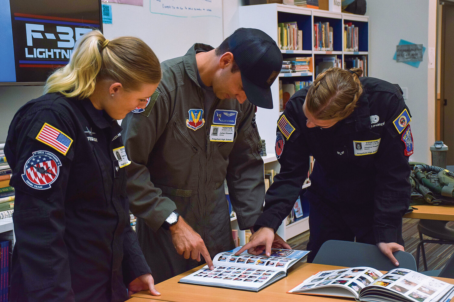 U.S. Air Force Capt. Julian Kinonen, center, looks at old yearbook photos of himself alongside Air Force Senior Airmen Kaitlyn Ergish, left, and Jessica Peiper, right, at Ridgefield High School on May 18.