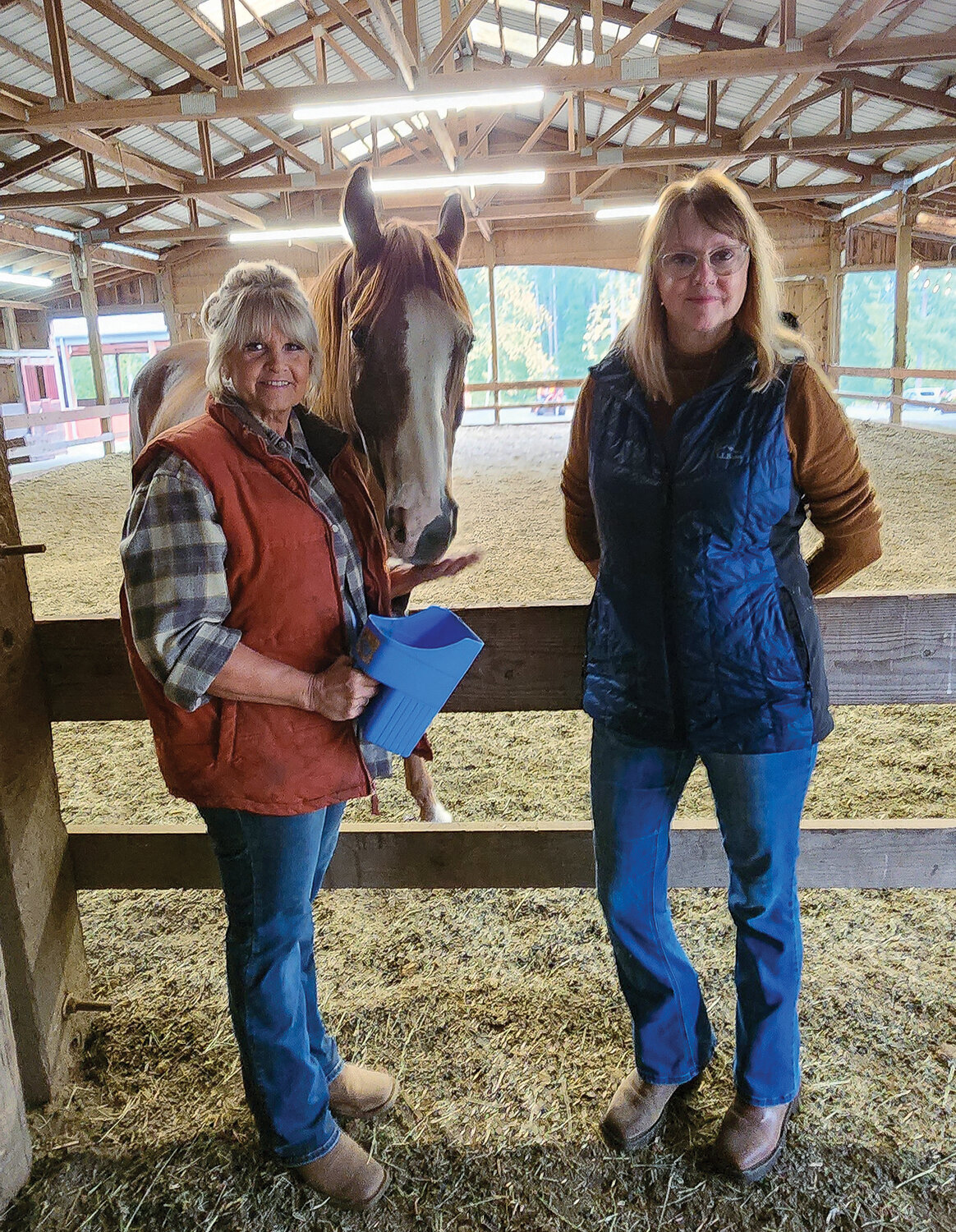 Owner Robin Nelson and volunteer Anne Justice stand beside Wrangler, one of the program’s therapy horses.