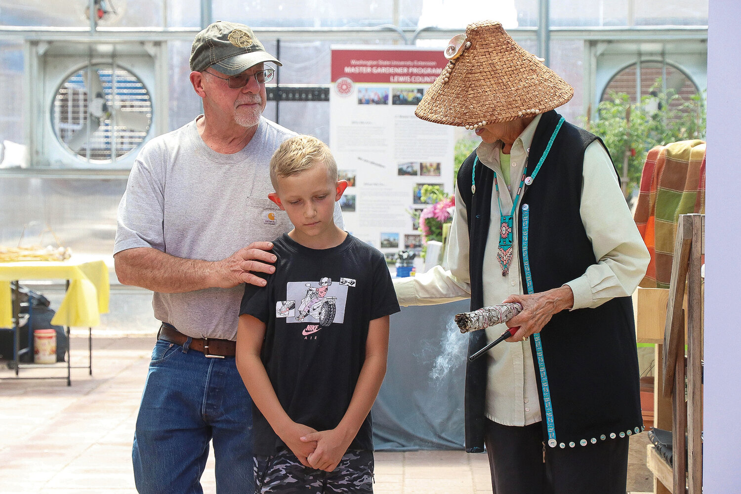 Cowlitz Indian Tribe Culture Board President John O’Brien and Cowlitz Indian Tribe Elder and Spiritual Leader Tanna Engdahl lead Owen, a Toledo Elementary School student and son of a Cowlitz Indian Tribe employee, on a spirit walk inside the new Toledo Learning Garden greenhouse on Saturday, Aug. 26.