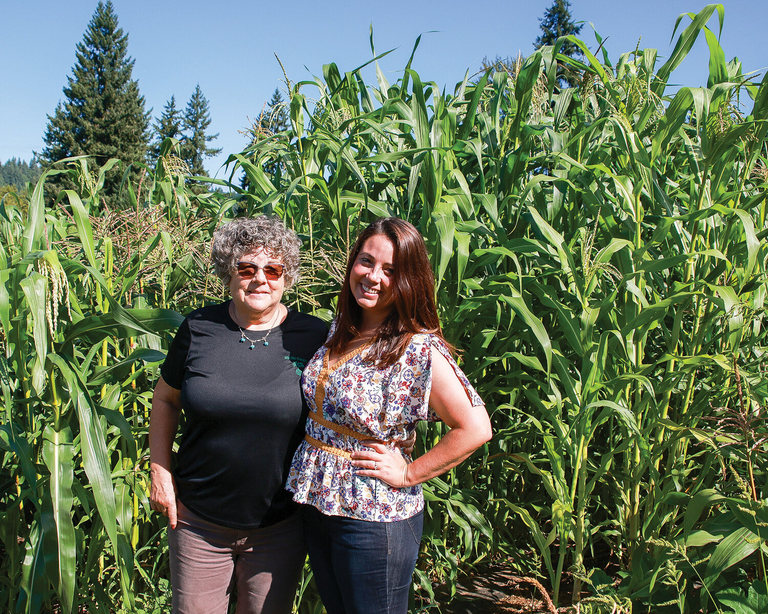 The owners of Mindful Creations LLC, Judy Canter, left, and Diana Peterson stand amid corn in their produce field on Sept. 6