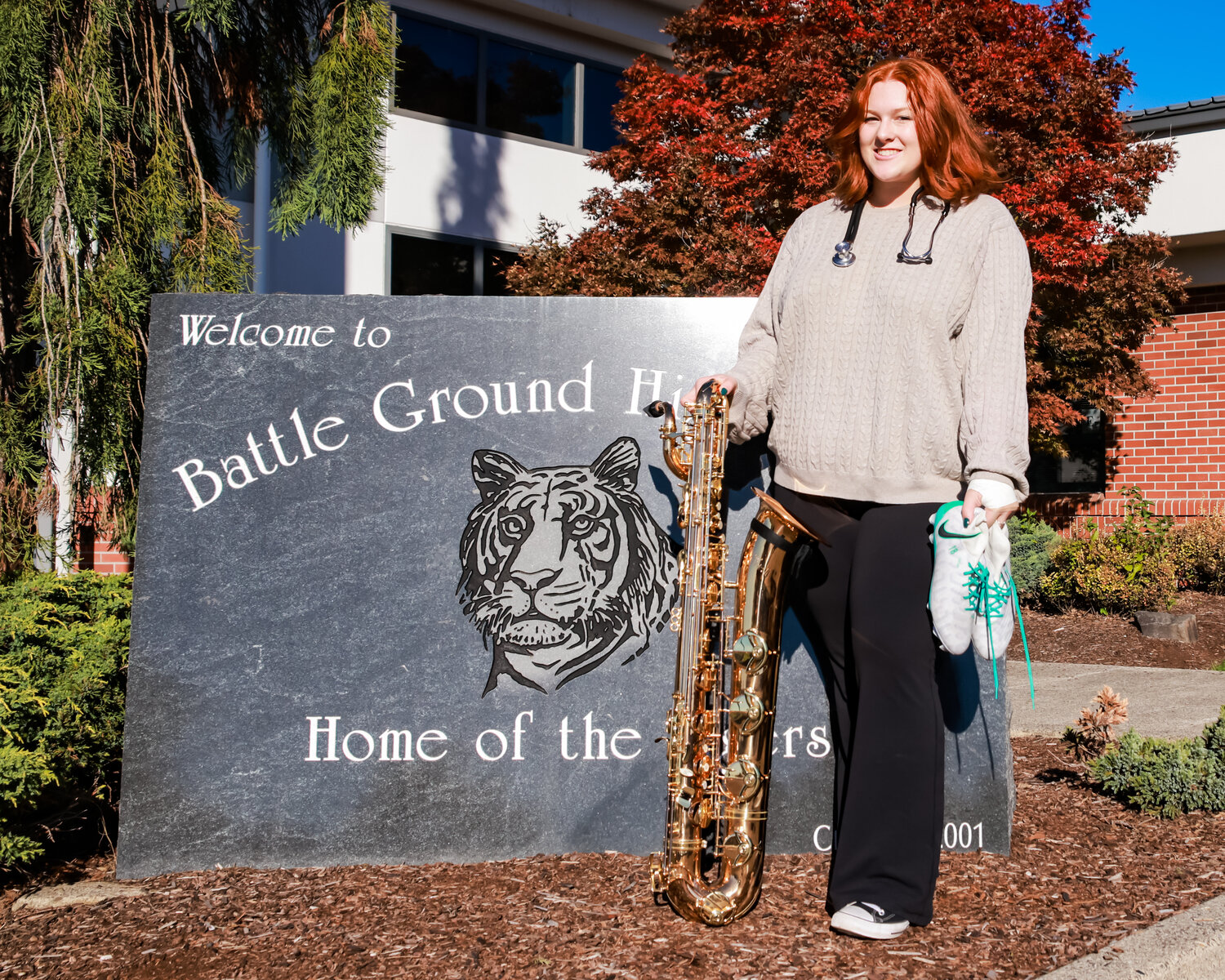 Battle Ground High School senior Clair Moss stands in front of the school with her stethoscope representing her participation in HOSA, her saxophone for band and her soccer cleats for her time as varsity goalie for the Tigers’ girls soccer team.