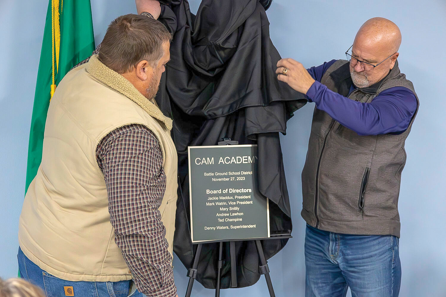Facilities manager Josh Joner, left, and Executive Director of Facilities and Operations Kevin Jolma unveil the dedication plaque at CAM Academy’s new campus on Monday, Nov. 27.