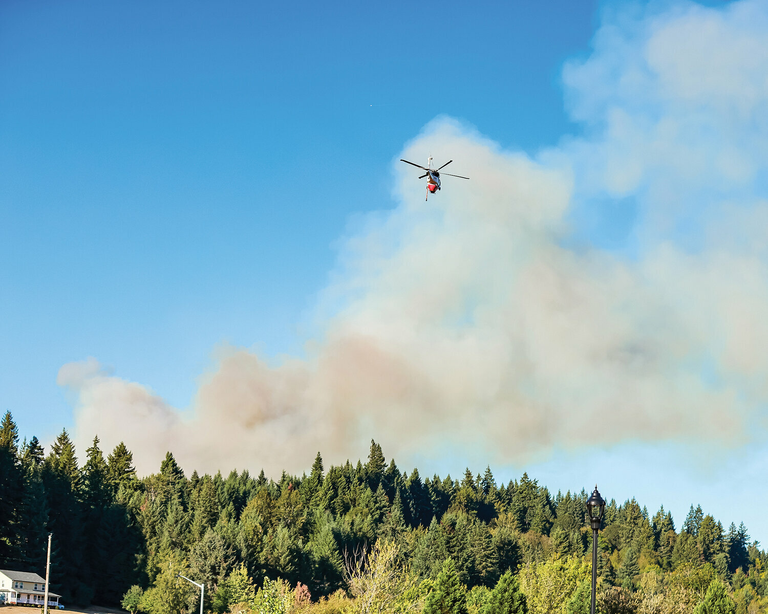 A helicopter aids in the firefighting effort during the La Center wildfire in August. The La Center fire burned 34 acres of property and caused evacuations on Aug. 16.