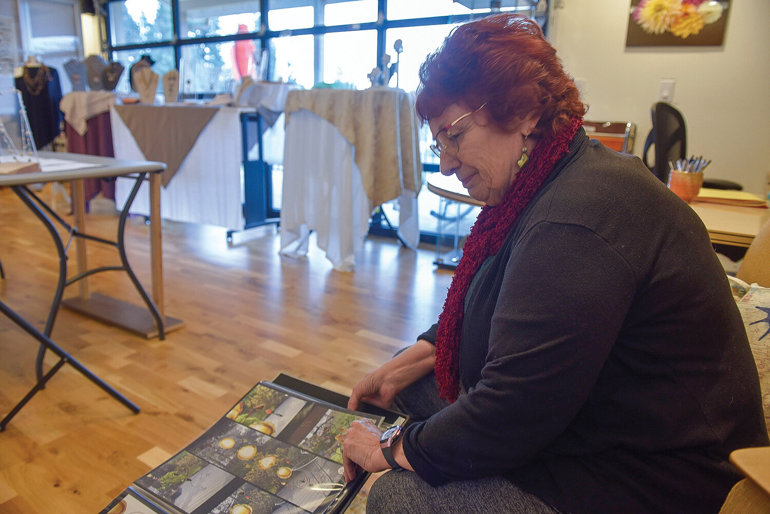 Jewelry artist Lois Steiner flips through a binder containing photographs of the art she’s created over the years.