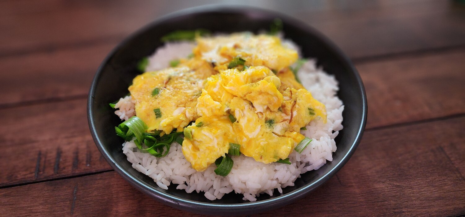 Half Moon Farm eggs cook into a bright yellow scramble, served with green onions and rice.